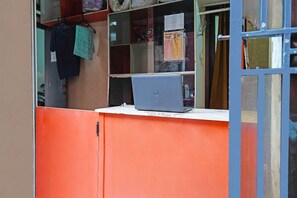 A laptop on a white counter with a red cabinet behind it. - Spot On 91783 Urban Syariah Residence (Bandung)