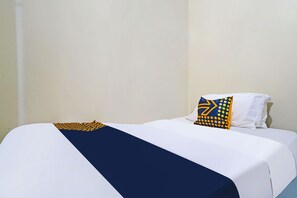 A bed with white bedding and a blue accent, a pillow with a geometric pattern, and a plain wall. - Spot On 91783 Urban Syariah Residence (Bandung)