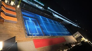 Una piscina con un borde de baldosas y una zona con alfombra roja.