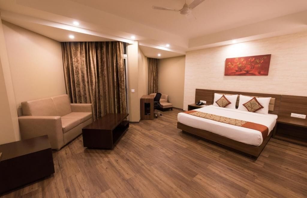 A hotel room with a bed, a sofa, a desk, and a chair.
