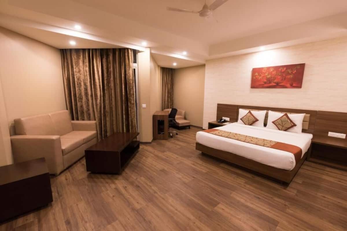 A hotel room with a bed, a sofa, a desk, and a chair.