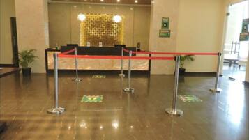 A reception area with a counter, red rope barrier, and a decorative wall.