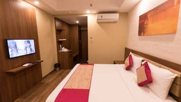 Une chambre d’hôtel équipée d’un lit, d’un téléviseur fixé au mur, d’un plancher en bois et d’un appareil de climatisation.
