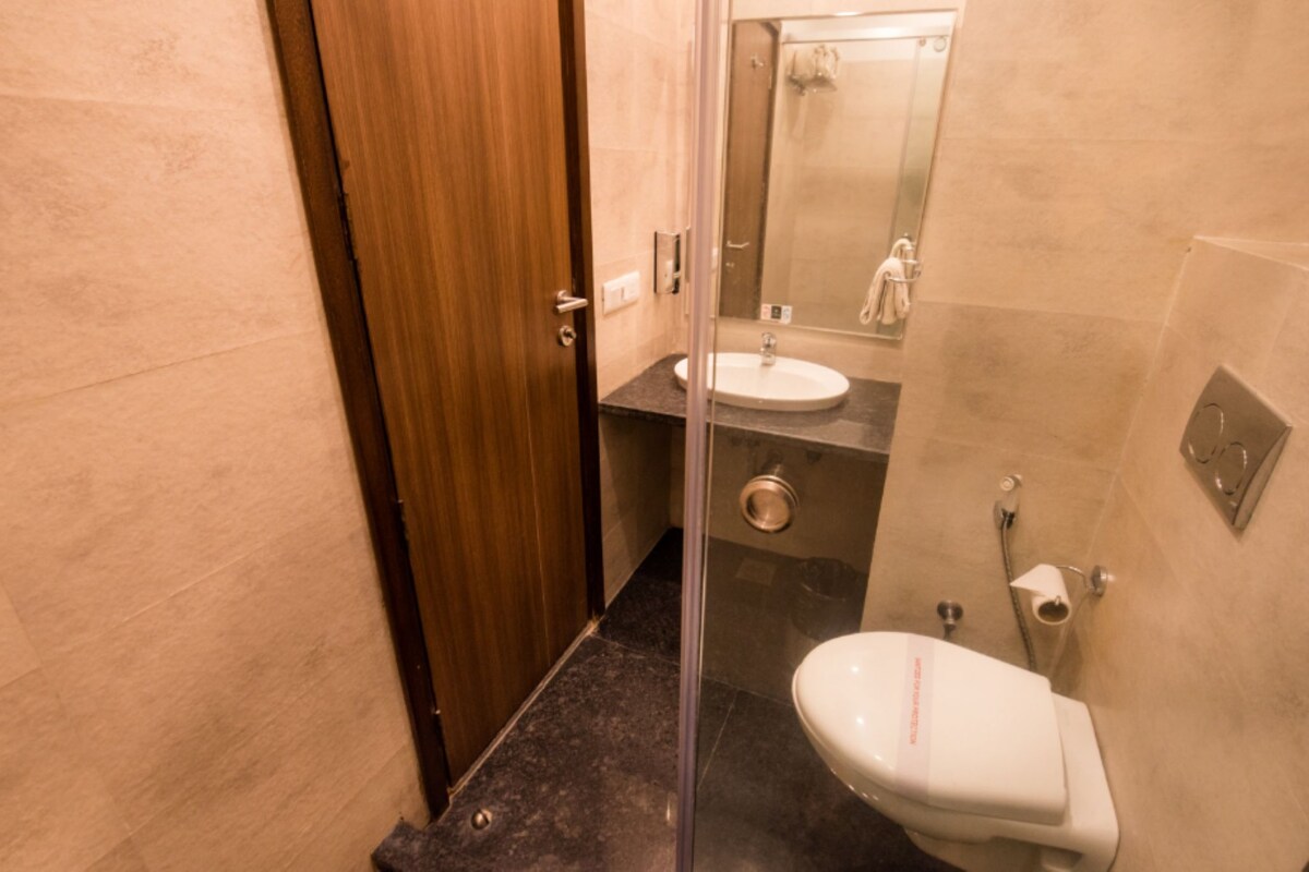 Une salle de bain avec une porte en bois, une douche en verre, un lavabo et des toilettes.