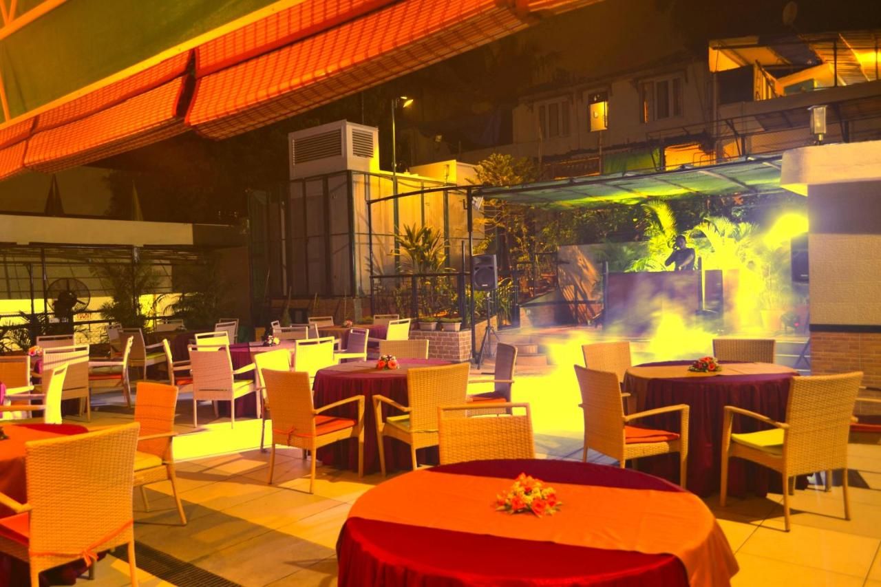 An outdoor dining area with tables and chairs, a fire feature, and a covered seating area.