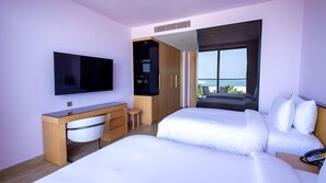 A hotel room with a TV, a desk, two beds, a wardrobe, and a balcony with a view. - Voco Dubai Monaco Heart of Europe (Dubai)