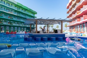 A swimming pool with lounge chairs, a bar area, and multi-story buildings with balconies. - Voco Dubai Monaco Heart of Europe (Dubai)
