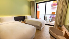 A hotel room with two beds, a small table, a chair, and a balcony with a view of a building and flowers. - Voco Dubai Monaco Heart of Europe (Dubai)