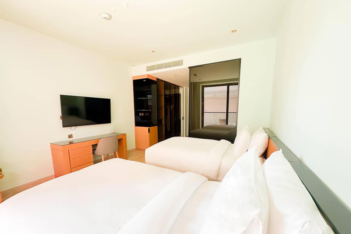 A hotel room with a bed, a desk, a chair, a TV, and a window.