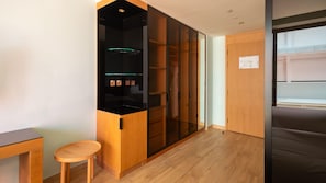 A modern room with a wooden cabinet, a small wooden stool, and a large wardrobe with glass doors. - Voco Dubai Monaco Heart of Europe (Dubai)