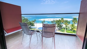 A balcony with two chairs, a small table, and a view of a beach and ocean. - Voco Dubai Monaco Heart of Europe (Dubai)