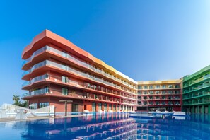 Un hôtel à plusieurs étages doté de balcons, d’une piscine et de bateaux.