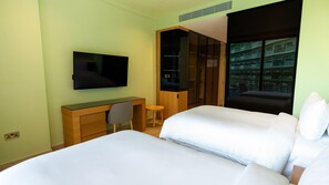 A hotel room with a bed, a desk, a chair, a TV, and a large window. - Voco Dubai Monaco Heart of Europe (Dubai)