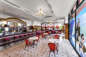 Un espace bar avec des tabourets, des tables et un comptoir où sont exposés divers articles.