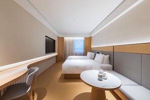 Ein Hotelzimmer mit einem Bett, einem Nachttisch, einem Stuhl und einem runden Tisch mit Tasse und Untertasse.