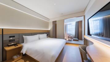 Een moderne hotelkamer met een groot bed, nachtkastje en een bureau met stoel.
