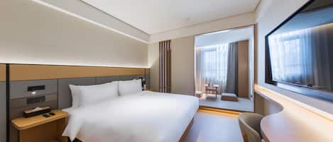 Una habitación de hotel moderna con una cama grande, una mesita de noche y un escritorio con una silla.