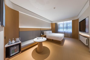 Une chambre d’hôtel moderne équipée d’un lit, d’une télévision, d’une petite table et d’un coin salon.