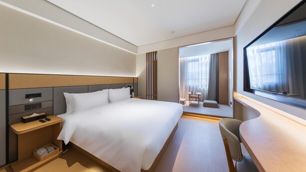 A modern hotel room with a large bed, bedside table, and a desk with a chair. - Ji Hotel Beijing Beiqing Road Zhongguancun Environ (Beijing)