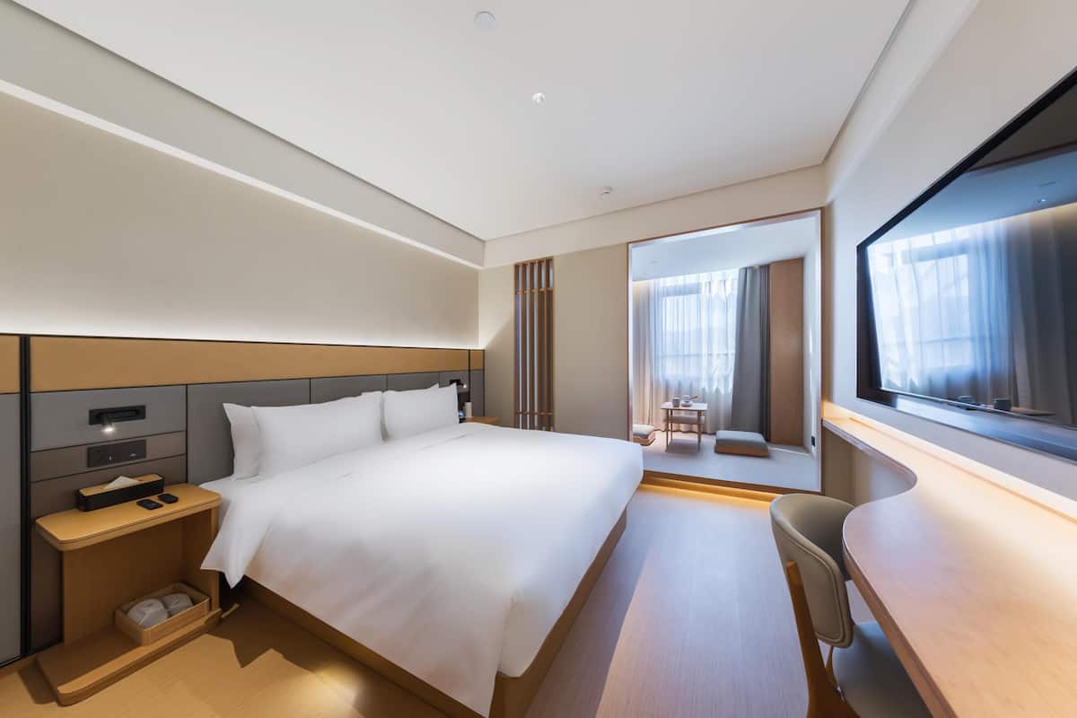 Ein modernes Hotelzimmer mit einem großen Bett, einem Nachttisch und einem Schreibtisch mit Stuhl.