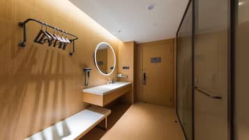 A modern bathroom with a wooden wall, a round mirror, a sink, and a bench.