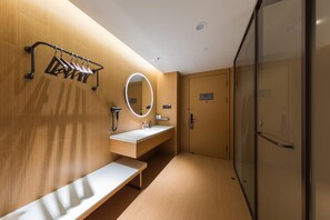 Ein modernes Badezimmer mit einer Holzwand, einem runden Spiegel, einem Waschbecken und einer Sitzbank.