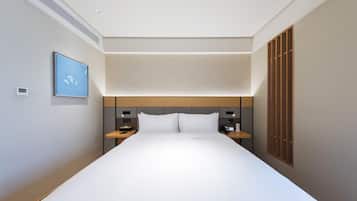 Una habitación de hotel moderna con una cama grande, mesitas de noche, un televisor de pared y una ventana con persianas.