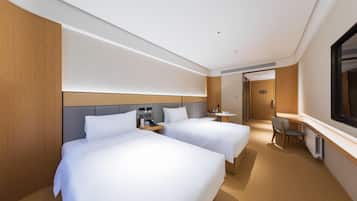 Ein Hotelzimmer mit zwei Betten, einem Schreibtisch, einem Stuhl und einem Fernseher.