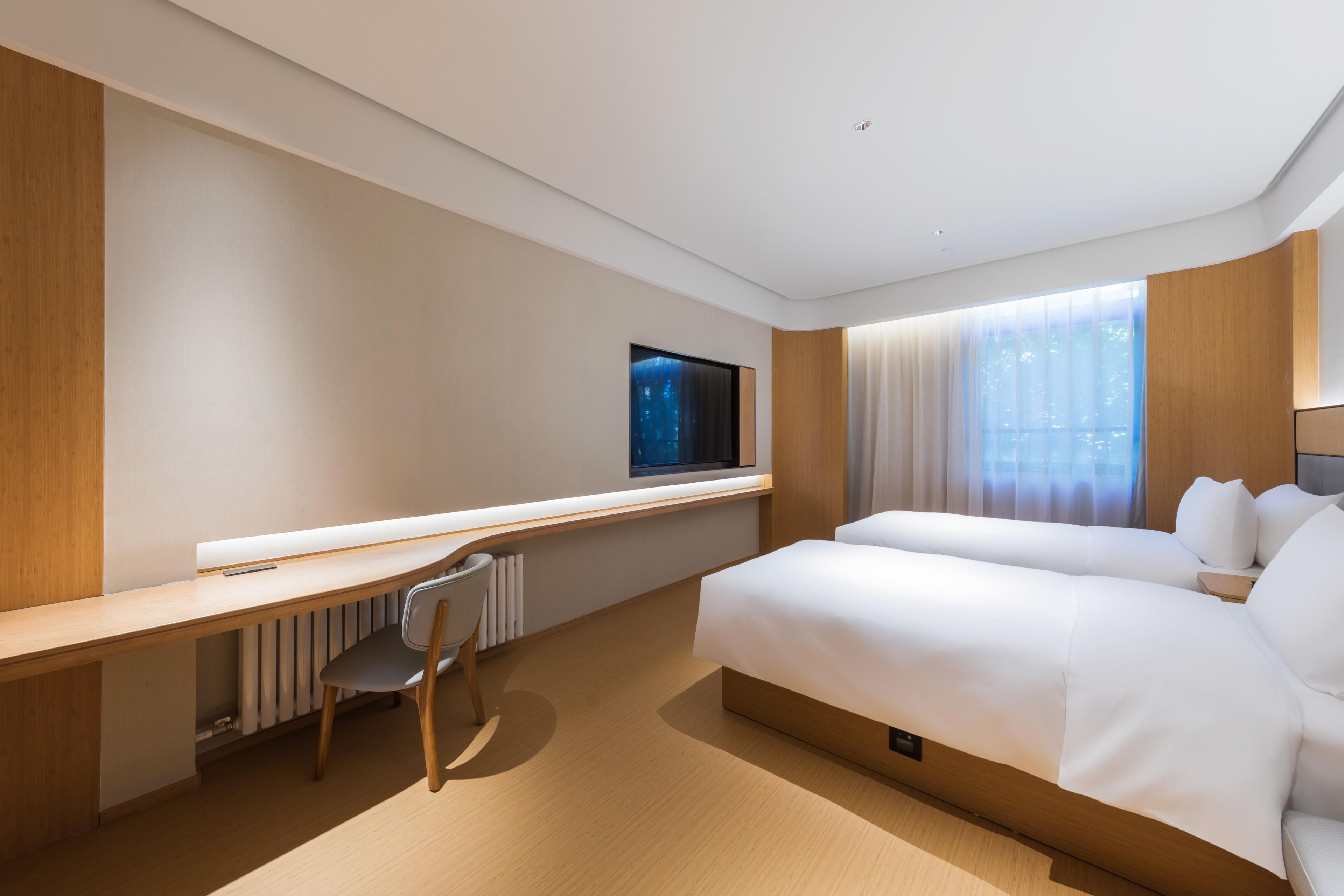 Una habitación de hotel moderna con una cama grande, un escritorio y un televisor.