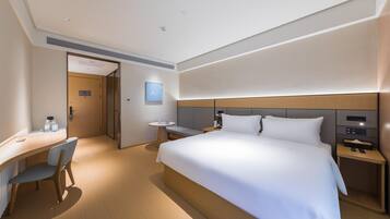 Een moderne hotelkamer met een groot bed, een bureau en een stoel.