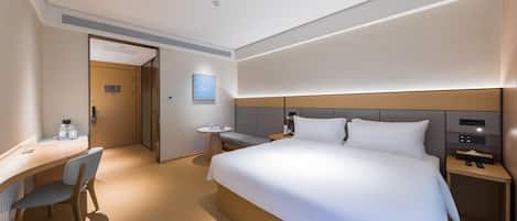 Ein modernes Hotelzimmer mit einem großen Bett, einem Schreibtisch und einem Stuhl.