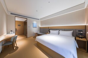 A modern hotel room with a large bed, a desk, and a chair.