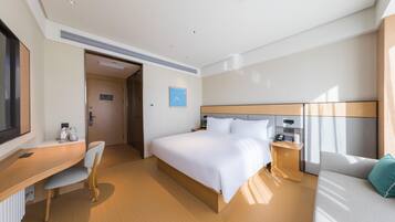 Quarto de hotel moderno com cama, escrivaninha, cadeira e televisão.