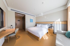 Quarto de hotel moderno com cama, escrivaninha, cadeira e televisão.