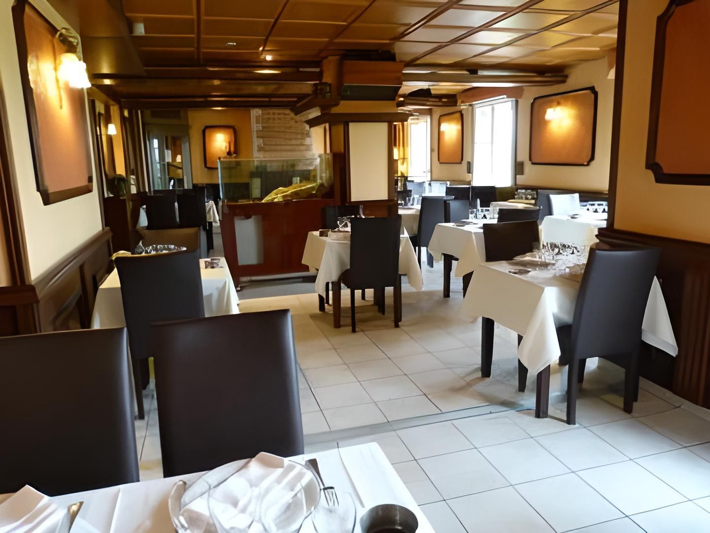 Ein Restaurantinneres mit Tischen, Stühlen, einer Theke und gerahmten Bildern an den Wänden.