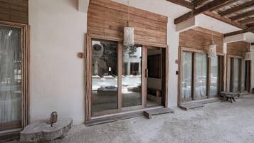 Un edificio con amplias puertas de cristal, vigas de madera y una lámpara colgante.