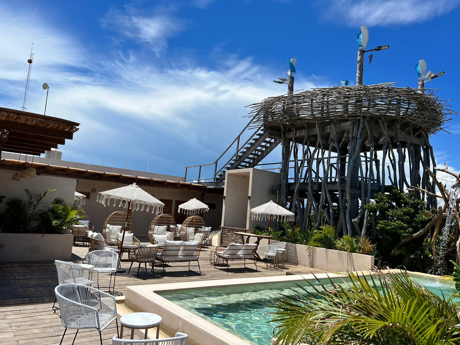 A pool area with lounge chairs, umbrellas, and a unique wooden structure.