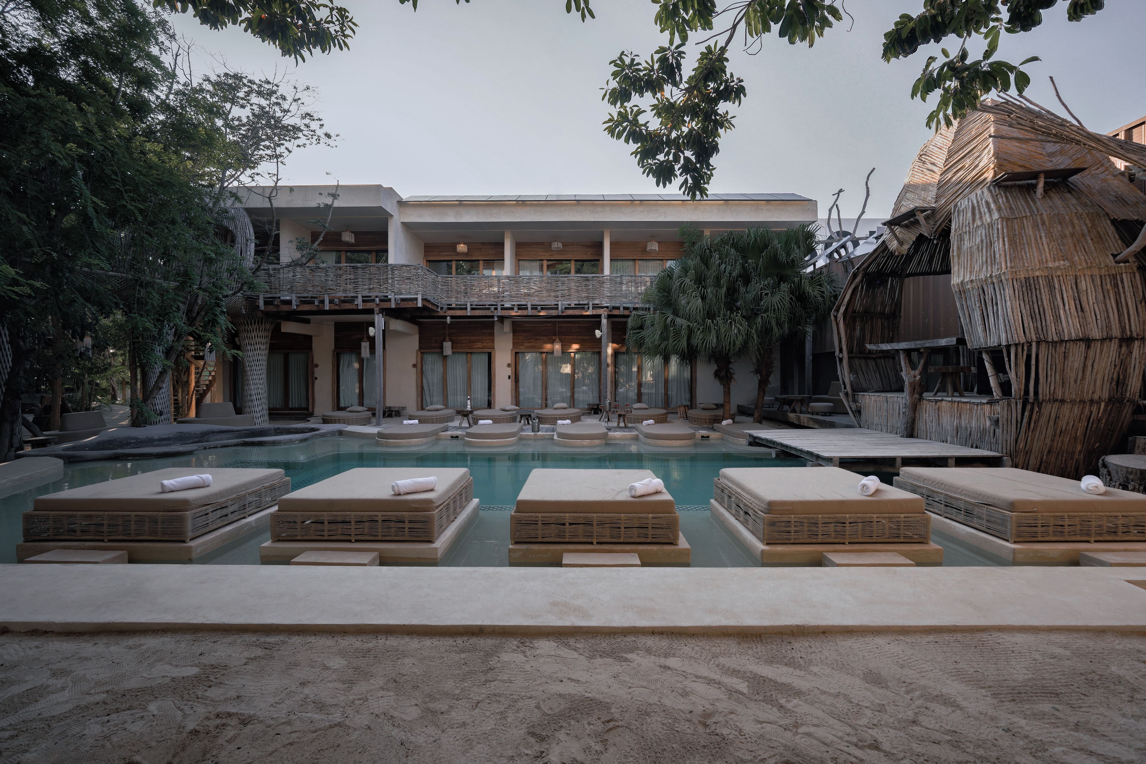 A pool area with lounge chairs and a building with a balcony.