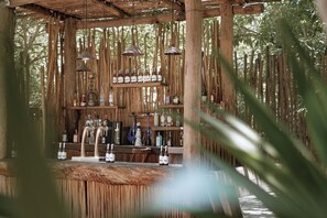 A rustic wooden bar area with hanging pendant lights, shelves of bottles, and a counter. - Cervecería Tulum Boutique Hotel & Beer Spa (Tulum)