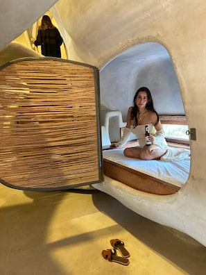 A person sitting on a bed inside a geodesic dome structure with a straw-like material wall. - Cervecería Tulum Boutique Hotel & Beer Spa (Tulum)