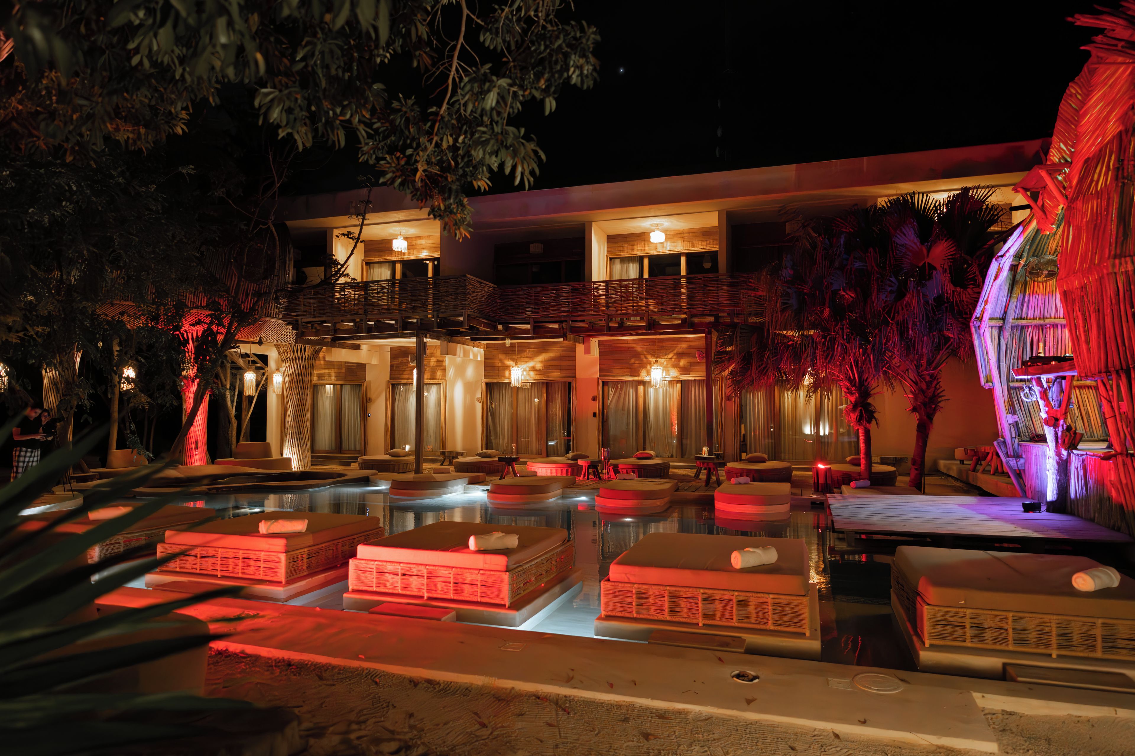 Un hotel con zona de piscina, varios balcones y un exterior bien iluminado.