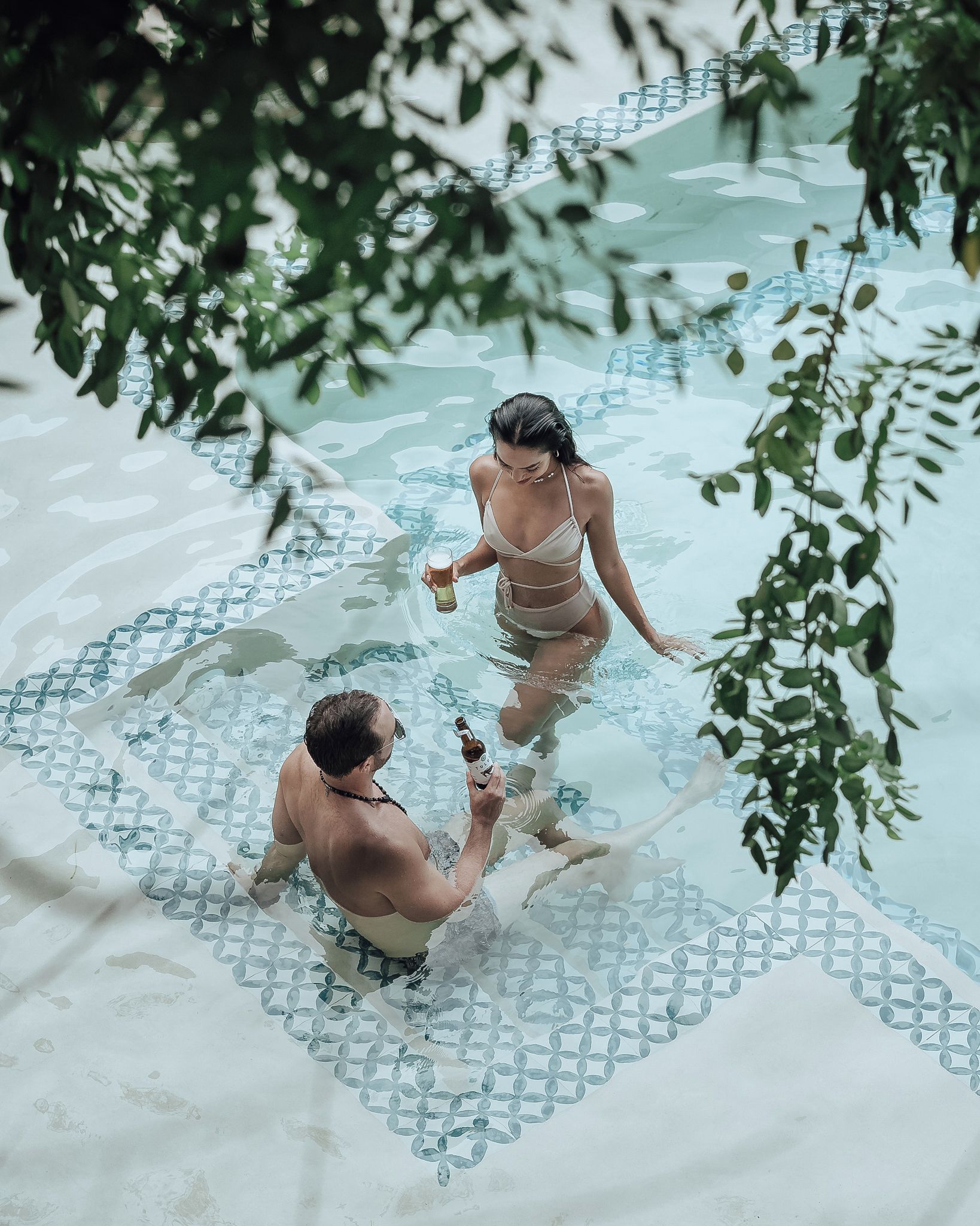 Dos personas en una piscina con un diseño geométrico en el suelo.
