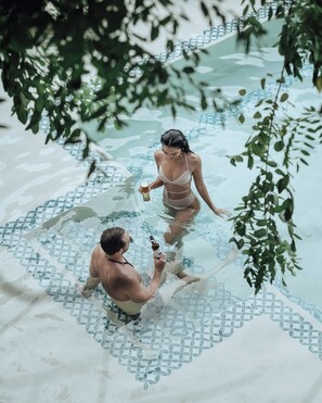 Dos personas en una piscina con un diseño geométrico en el suelo.