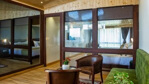 A room with a wooden ceiling, large windows, a bed, a green sofa, and a chair. - Sumitel Vista 800m From Mall Road (Darjeeling)