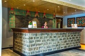 A reception desk with a stone facade, a wooden ceiling, and decorative wall patterns. - Sumitel Vista 800m From Mall Road (Darjeeling)