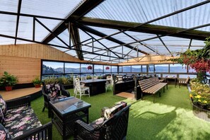 Ett växthus med träinredning, sittplatser och utsikt över bergen.