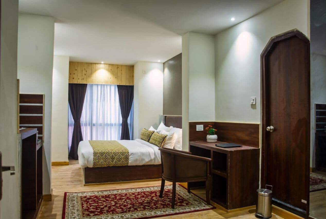 Ein Hotelzimmer mit Bett, Schreibtisch, Stuhl und Mülleimer.