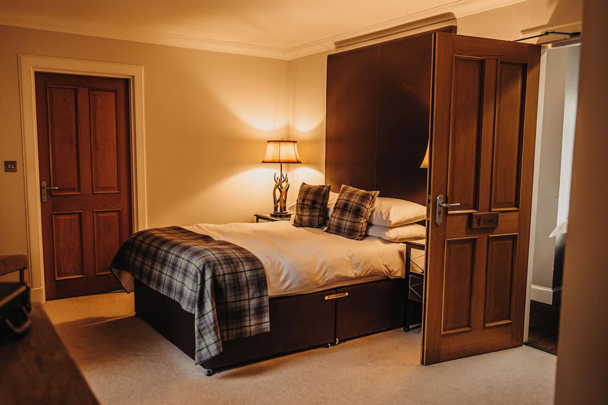 A bedroom with a bed, a nightstand, a lamp, and a wardrobe.
