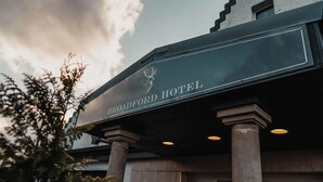 The exterior of the Broadford Hotel with a signboard, columns, and a clear sky.