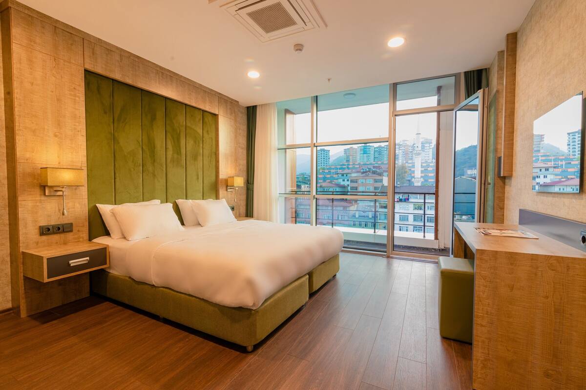 Ein modernes Hotelzimmer mit einem großen Bett, einem Schreibtisch und Blick auf die Stadt.